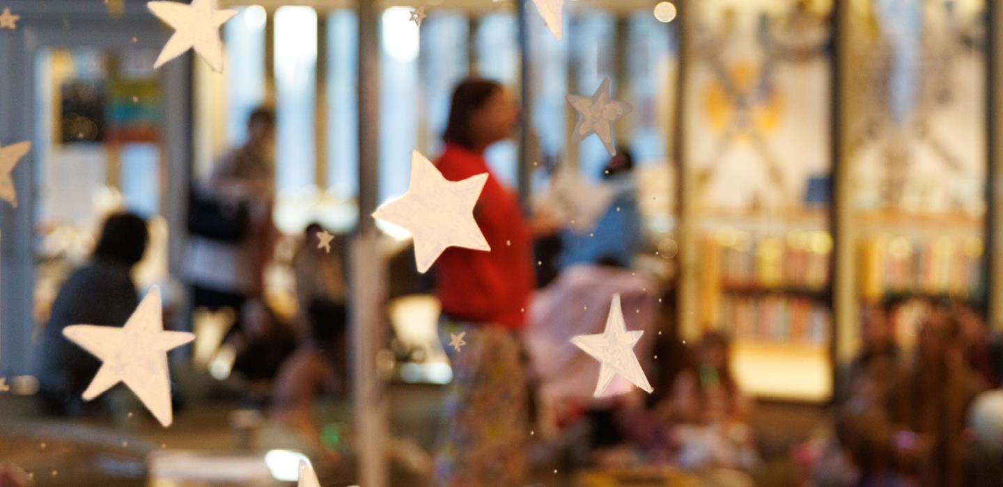 Close up of starts stuck to the glass wall on Level 4 of the Library, with a pyjama storytime in the background.