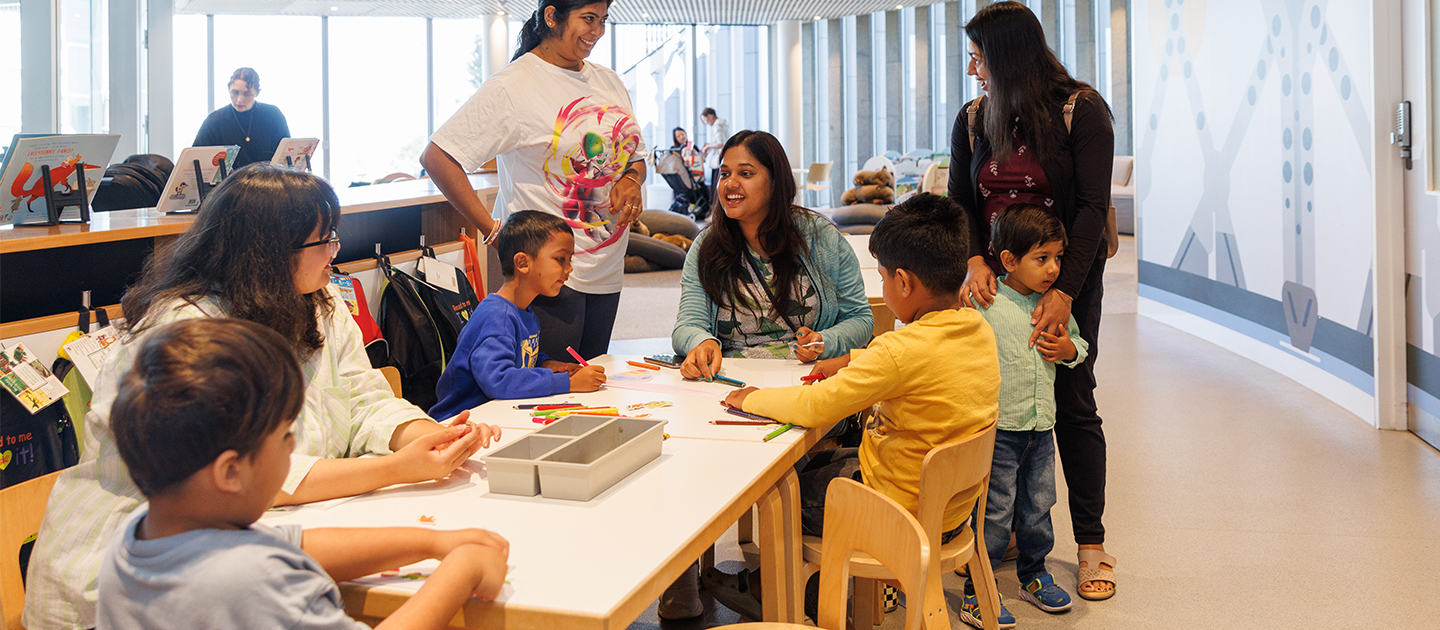 Children and parents colouring in at the tables on Level 4 of the Library.
