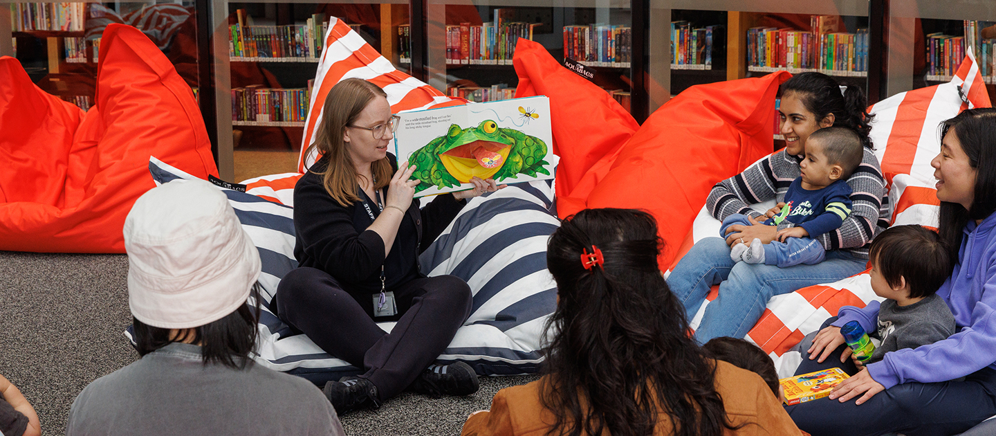 Library presenter reading to mothers and children.