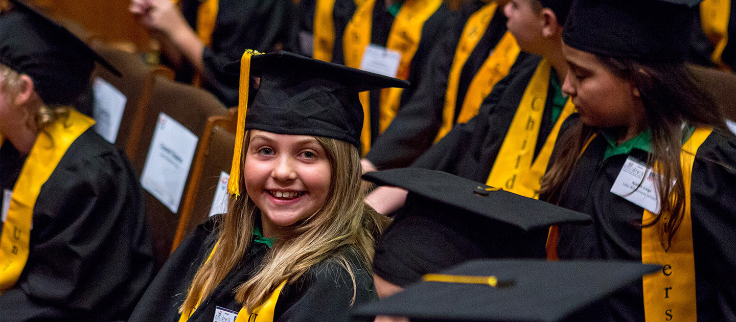 Children in university graduation gowns