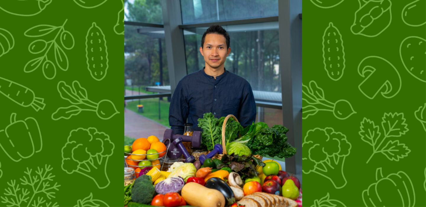 Dr Marc Sim in front of a range of colourful fruits and vegetables.
