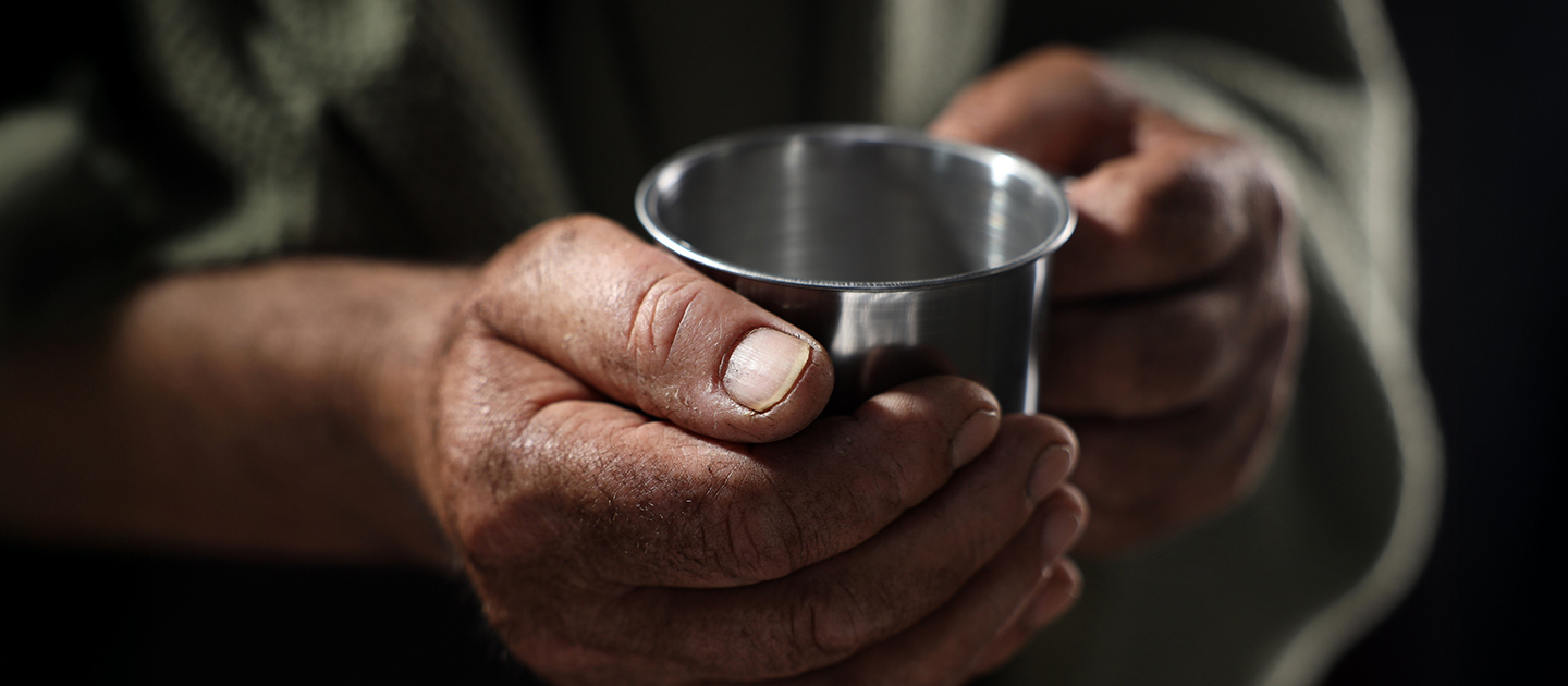 Close up photograph of hands holding a tin cup.
