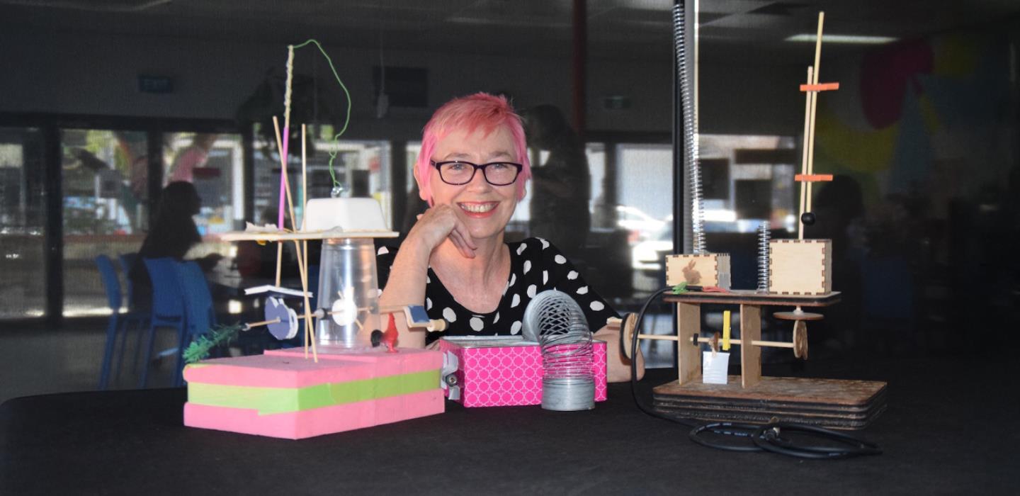 Dr Claire Pannell sitting with some of her extraordinary musical instruments, made from everyday objects.