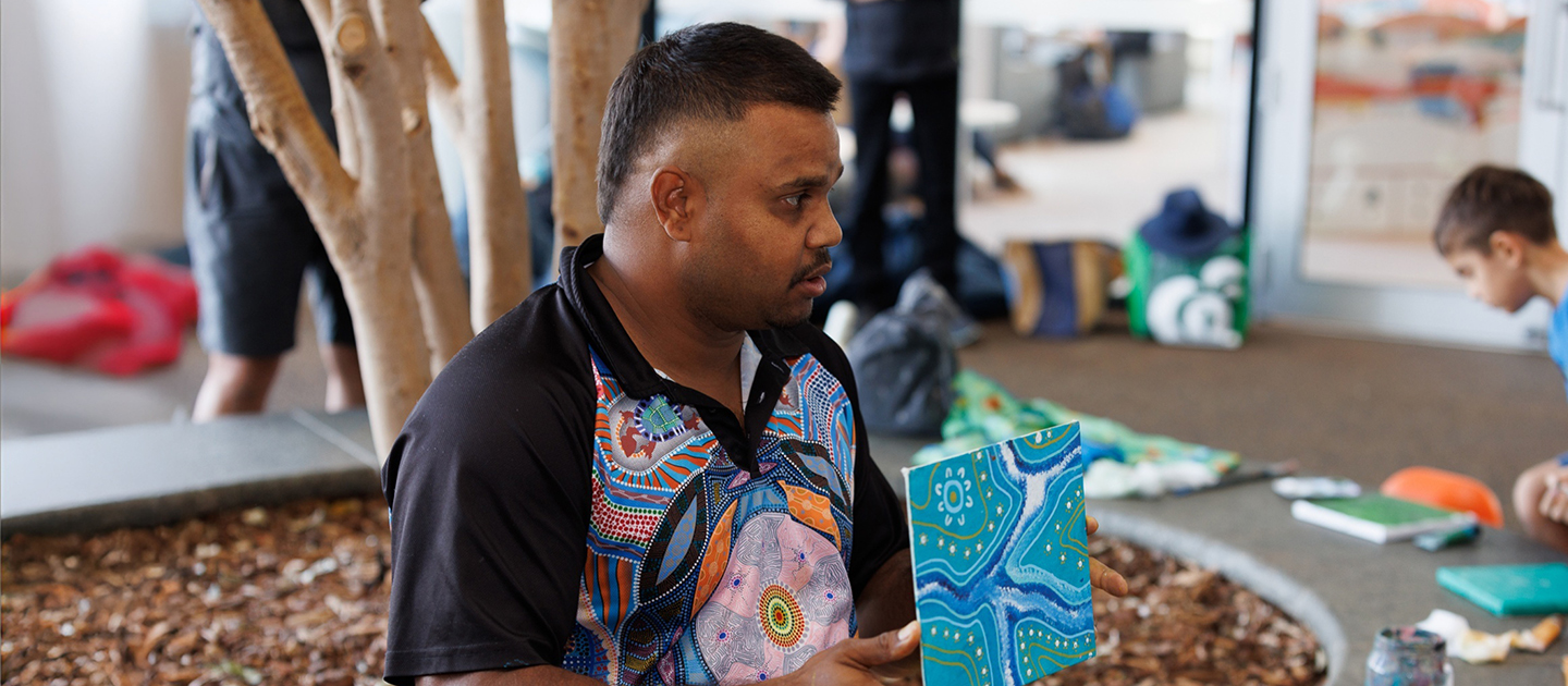 Justin Martin holding artwork from a traditional art workshop on Level four of the Library.