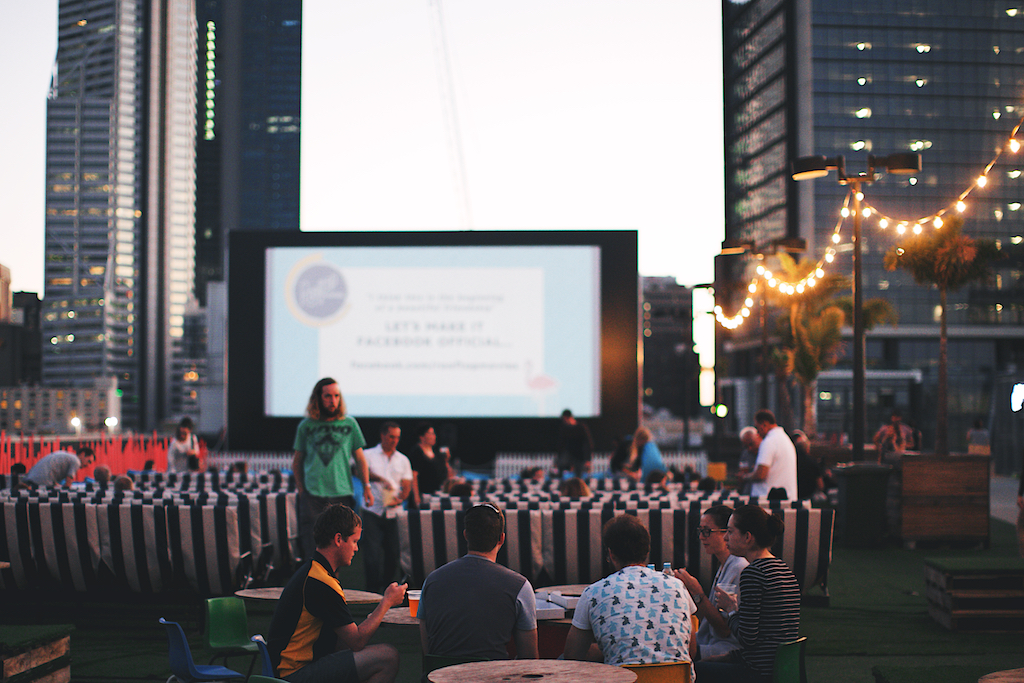 People eating in front of rooftop movie at sunset
