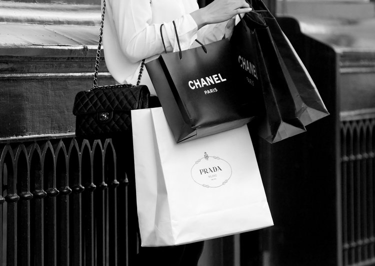 Person holding Chanel and Prada shopping bags