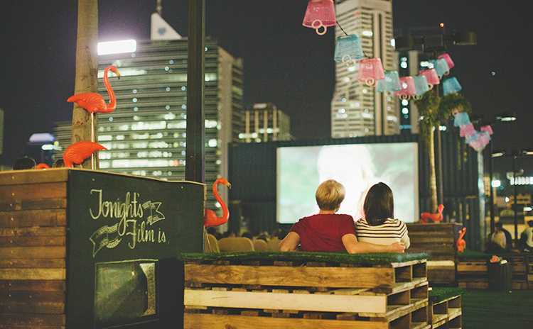 Couple watching a rooftop movie with city in background