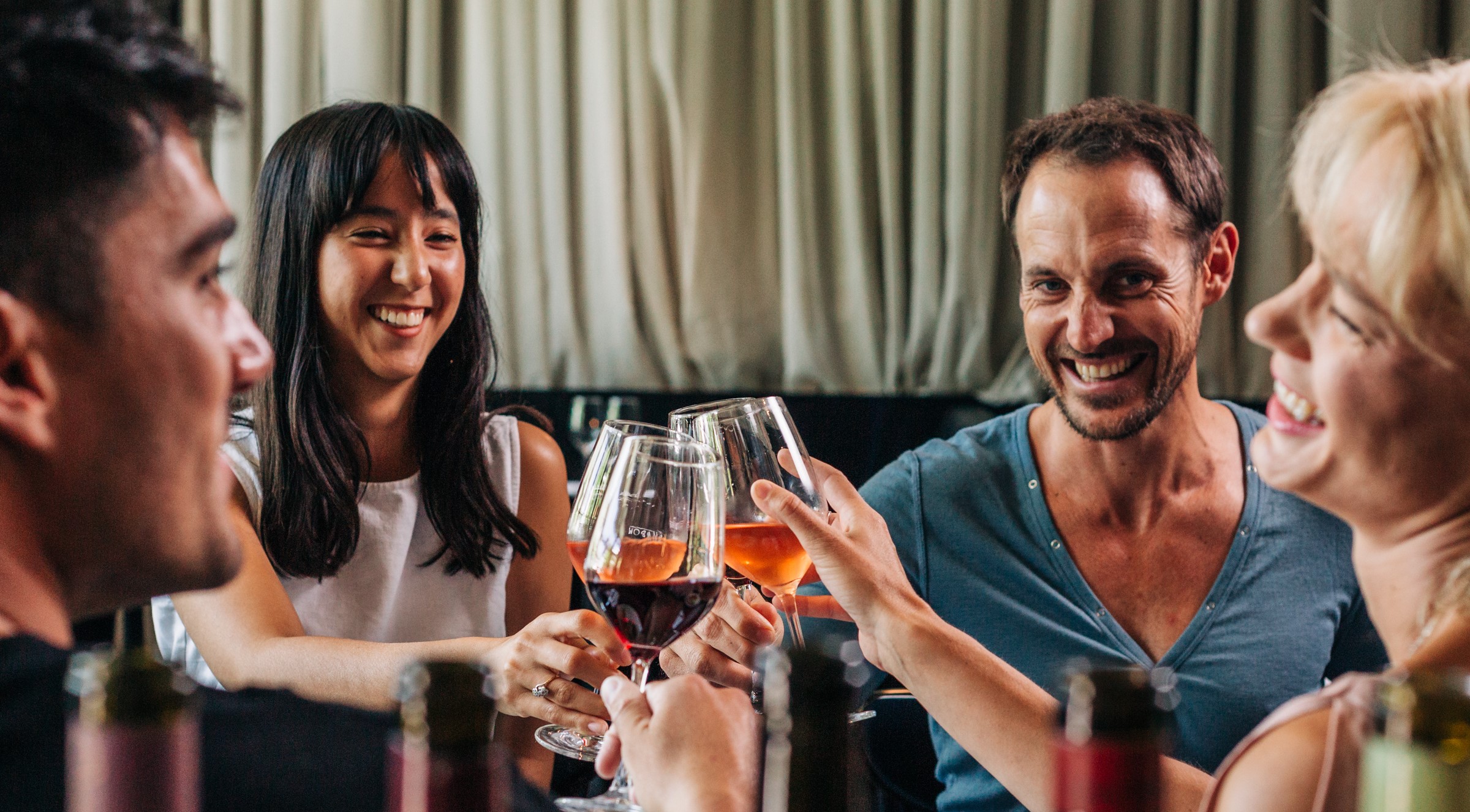 Four smiling people cheersing their wine glasses