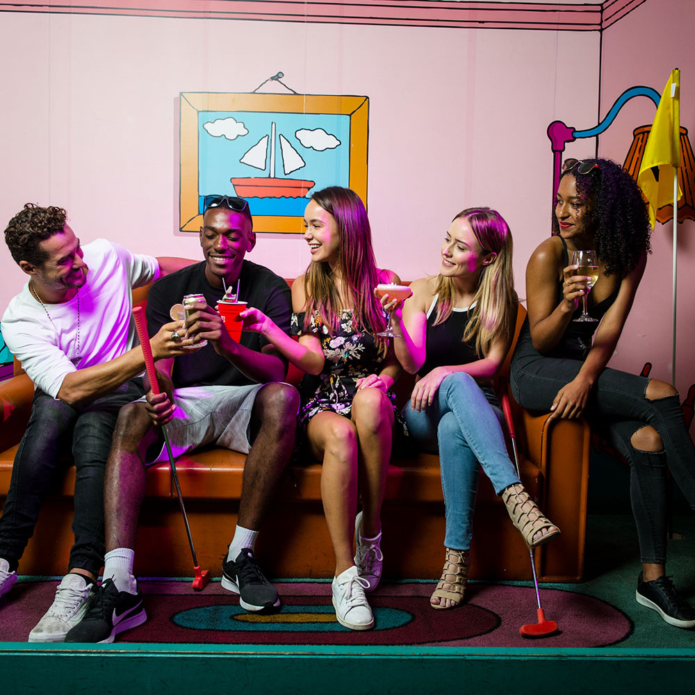 five people sitting on the Simpsons couch at Holey Moley