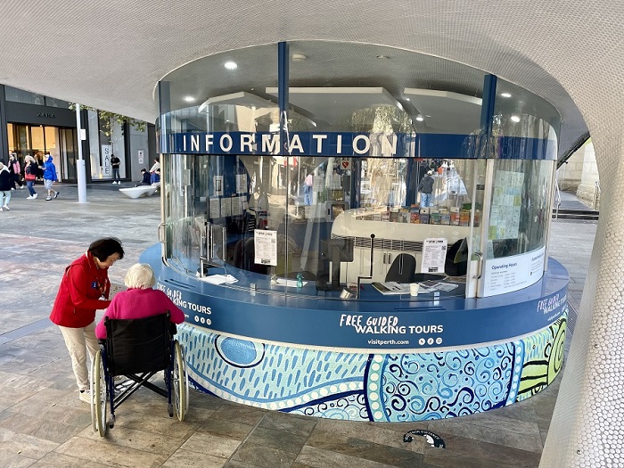 Person in wheelchair being assisted by a volunteer at iCity Kiosk